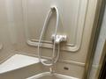 A showerhead with a flexible hose mounted on a beige wall inside a 2000 Ford Motorhome