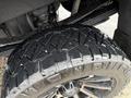 A close-up view of a rugged tire with deep tread used on a 2022 GMC Sierra 3500HD showcasing its traction design and black finish