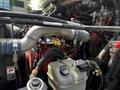 A 2010 Freightliner M2 106 engine with various pipes and wires prominently displayed along with a red component and fluid reservoir