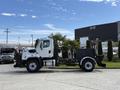 A 2016 Freightliner 108SD flatbed truck shown from the side with a white cab and black chassis standing on a paved surface