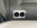 Two circular dials mounted on a rectangular panel with screws on a vehicle's interior wall
