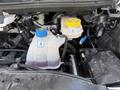 The image shows the engine compartment of a 2021 RAM Promaster featuring a coolant reservoir with blue caps and a translucent overflow tank with a yellow cap