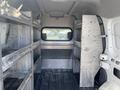 A 2013 Ford Transit Connect with empty metal shelving units inside the cargo area