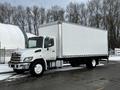 A 2019 Hino 338 truck with a 24-foot white cube-shaped cargo box and a silver front grille parked on a snowy road