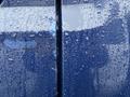 A close-up view of a blue 2011 GMC Sierra 3500HD door with water droplets clinging to the surface creating a textured appearance