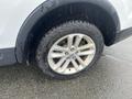 A close-up of the wheel and tire of a 2016 Ford Explorer showing a silver alloy rim and a treaded all-season tire with visible water droplets