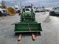 A 2003 John Deere 790 tractor with a front loader attachment and fork tines in the foreground