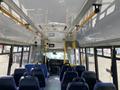 Interior view of a 2017 Chevrolet Express bus showing the seating area and driver's compartment with blue seats and yellow grab bars