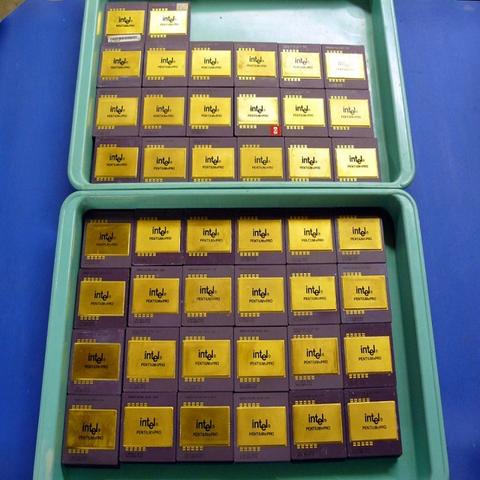 A collection of ceramic Intel CPU processors arranged in two trays with gold-colored surfaces and purple bottoms