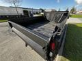 A 2018 Ford F-550 with a flatbed design and a black finish parked on a street showing the open truck bed