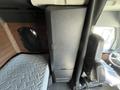 Interior view of a 2022 Freightliner Cascadia featuring a brown upholstered sleeping area and a black storage compartment with an ergonomic driver's seat visible