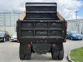 A 2017 Ford F-750 dump truck viewed from the rear with a black body and wooden bed emptying feature