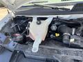 The image shows the engine compartment of a 2012 Chevrolet Express featuring the coolant reservoir battery and various engine components