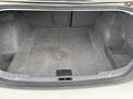 The image shows the trunk of a 2011 BMW 3-Series featuring a spacious carpeted interior with side compartments and no visible items inside
