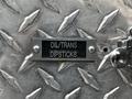 A metallic plate engraved with the words OIL/TRANS DIPSTICKS on a textured surface