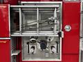 A red 1991 Sutphen Deluge fire truck panel featuring chrome valves hoses and a metal ladder clamp