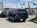 A blue 2015 Ford F-150 with a covered truck bed is parked facing away, showcasing its rear and chrome wheels
