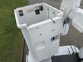 A white bucket attached to a boom lift of a 2005 Freightliner M2 106 with warning labels and a small window on the side