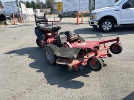 A red 2017 Ferries lawn mower with a riding seat two rotary blades and large rear wheels parked on a paved surface