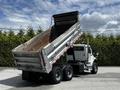 A 2010 Freightliner M2 106 dump truck with its bed raised, showing an empty metal container ready for unloading