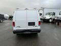 A white 2013 Ford Econoline van viewed from the rear with a blank license plate and no visible markings on the back