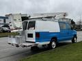 A blue and white 2009 Ford Econoline van with a raised bucket lift attached to the roof and equipment stored in the rear section