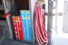 A 2012 Mercedes-Benz Sprinter van with colorful storage containers labeled for oil, antifreeze, and transmission fluid alongside coiled hoses