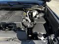The image shows the engine compartment of a 2023 Toyota Tundra with various components including the engine block air intake and fluid reservoirs