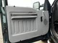 The interior door panel of a 2012 Ford F-550 featuring a gray finish with a handle and a vent area