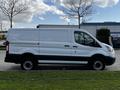 A white 2018 Ford Transit van with a smooth body and black trim parked on grass