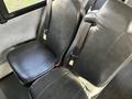 Two black vinyl bus seats with seatbelts positioned side by side in a vehicle interior