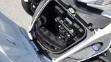 An open storage compartment of a 2013 Can-Am Spyder showing the battery and a black fabric cover inside