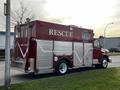 A red 1994 Freightliner FL80 emergency rescue vehicle with white trim and large silver side storage compartments marked with the word RESCUE