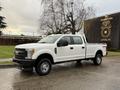 A white 2017 Ford F-350 SD truck with a double cab and an open bed parked on a wet surface