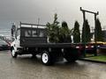 A 2006 Hino 155 flatbed truck with a black bed and side rails viewed from the rear showing wheels and undercarriage details