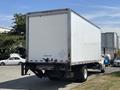 A 2015 Freightliner M2 106 box truck with a white cargo area and visible rear lights parked on a paved surface