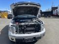 A 2012 Ford F-150 with its hood raised revealing the engine compartment and front grille