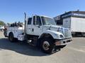 A white 2007 International 7300 truck with a utility body is shown, featuring multiple compartments and a large reel mounted on the side
