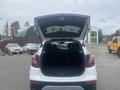 A 2018 Buick Encore with its rear hatch open revealing the spacious cargo area and back seats in a neutral color