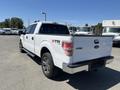 A white 2014 Ford F-150 XTR pickup truck with a black bed and stylish wheels parked in an outdoor area