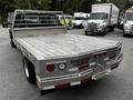 A 2008 Ford F-550 with a flatbed design featuring a wooden surface and red reflective stripes on the rear side