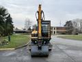 A 2022 Hyundai R55-9A excavator facing forward with a yellow arm and a large gray bucket attached at the front
