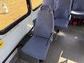 Interior view of a 2017 Chevrolet Express showing an empty blue fabric seat with armrests positioned beside other seats in a commercial van setting