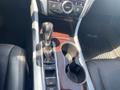 The interior of a 2017 Acura TLX featuring a gear shift lever a glossy wood trim console and buttons for various driving functions