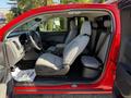 A 2018 GMC Canyon with a red exterior and a light gray interior featuring two front seats and a rear bench seat visible from the open driver's side door