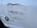 A white 2014 Chevrolet Express with visible damage on the side showing deep scratches and a dent