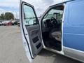 A 2009 Ford Econoline van with the driver's side door open revealing the interior including the dashboard and front seat