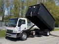 A 2009 Ford LCF 550 dump truck with a tilted dump bed showcasing its cargo area and a white and silver color scheme
