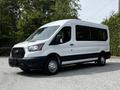 A 2022 Ford Transit van in white with black accents parked with a large windowed side and a sleek design