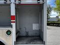 A 2009 Ford F-550 with an empty cargo area featuring a metal floor and drainage grate visible in the center